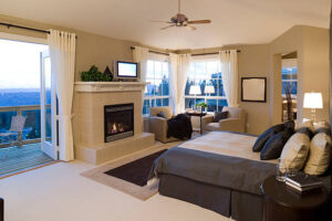 A cozy bedroom featuring a bed and a fireplace, designed by Creative Solutions for a warm and inviting atmosphere.